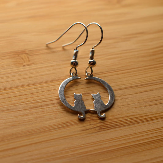 Close up of two cat on moon earrings on drop hooks